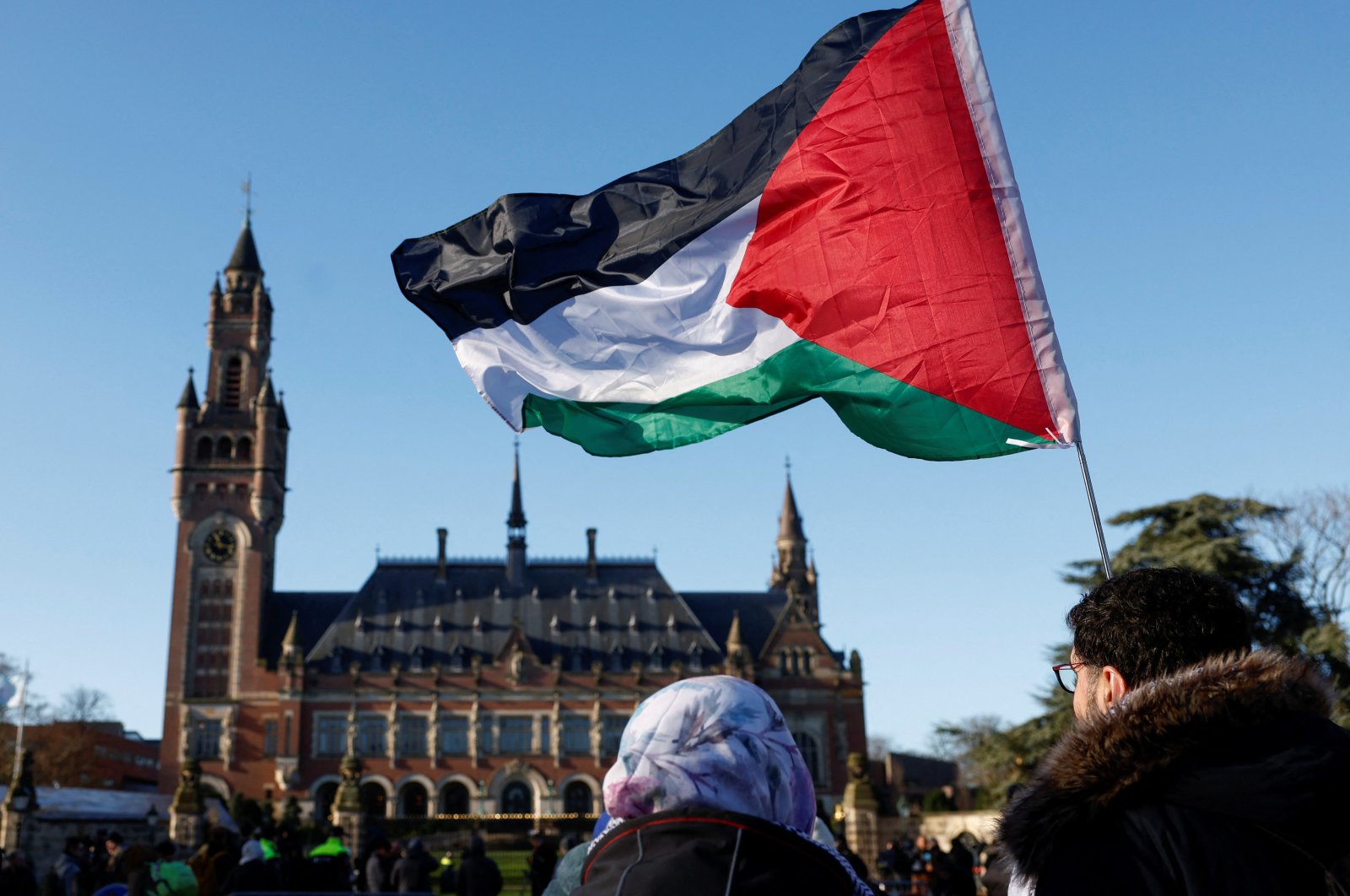 Protesters hold a Palestinian flag as they gather outside the International Court of Justice (ICJ) as judges rule on emergency measures against Israel following accusations by South Africa that the Israeli military operation in Gaza is a state-led genocide, the Hague, Netherlands, Jan. 26, 2024. (Reuters Photo)