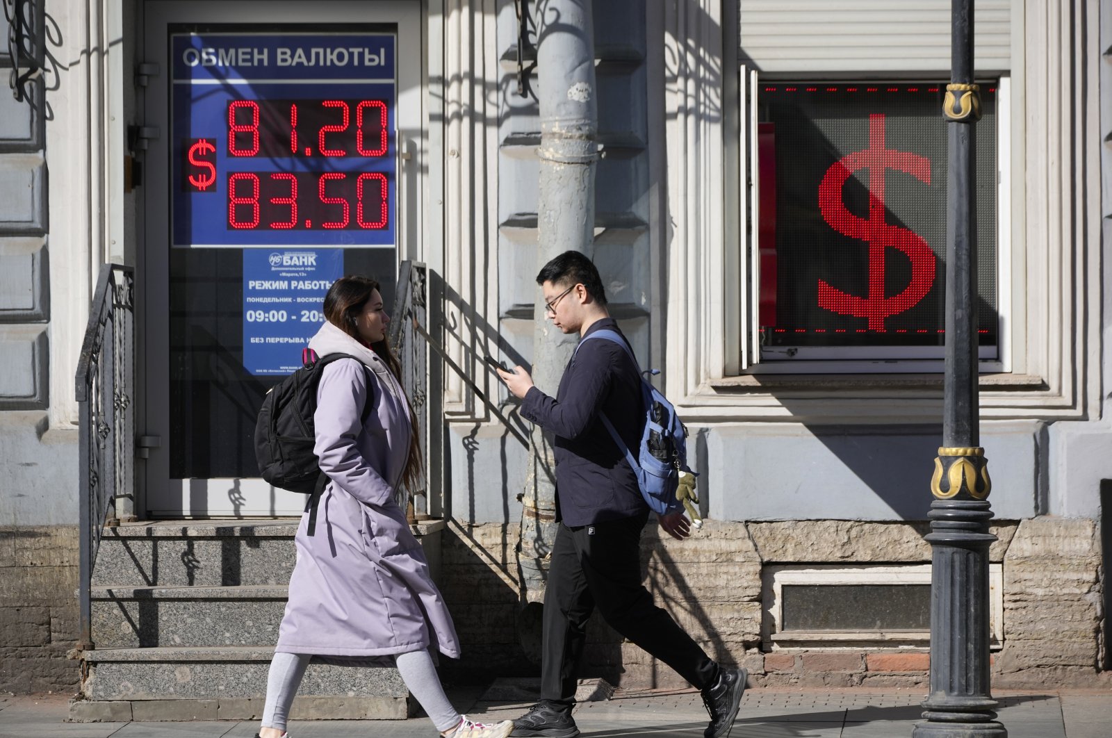 People walk past an exchange office screen showing the currency exchange rates of the U.S. dollar to the Russian ruble in St. Petersburg, Russia, April 7, 2023. (AP Photo)