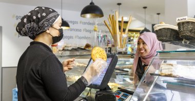A smiling woman wearing a Muslim headscarf (hijab) buying food from a bakery at an unspecified location in this undated file photo. (Getty Images, File Photo)