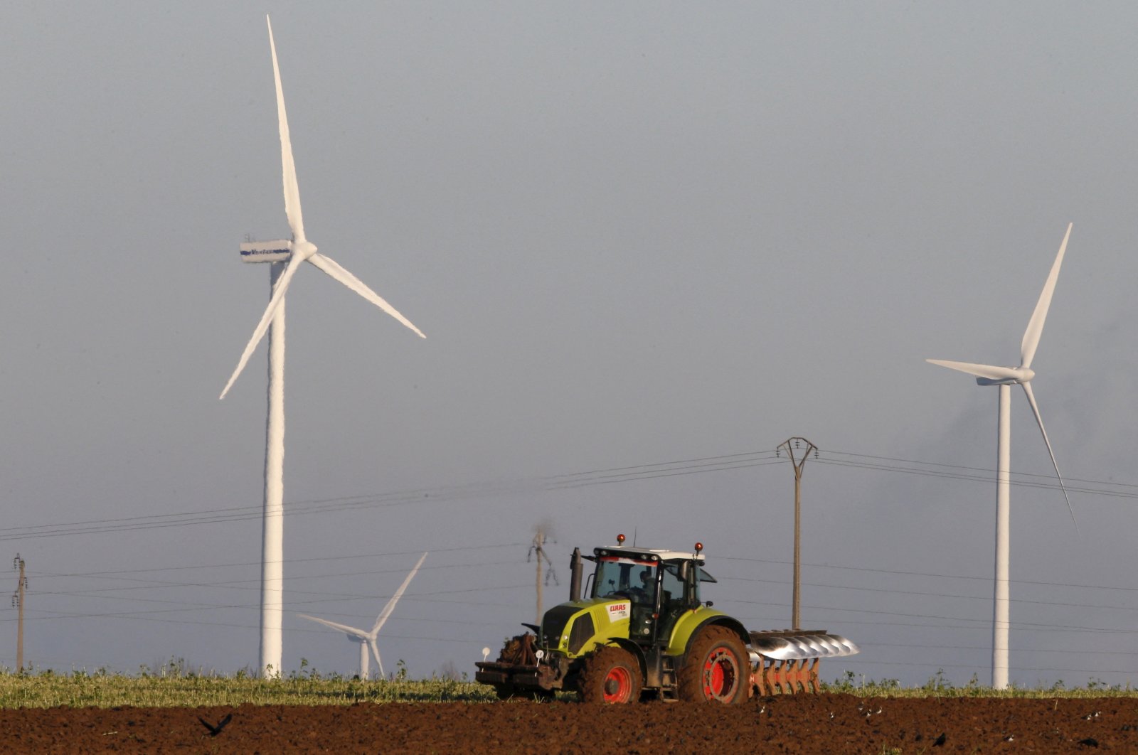 A French farmer drives a tractor as he plows a field in front of power-generating windmill turbines on a wind park in Vauvillers, near Amiens, France, Nov. 23, 2015. (Reuters File Photo)