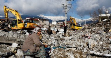 A woman sits amidst rubble and damage following a pair of powerful earthquakes, in Gaziantep, southeastern Türkiye, Feb. 7, 2023. (Reuters Photo)