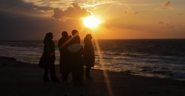 Palestinian girls look at the sunset on a beach in Deir Al-Balah town, southern Gaza Strip, Palestine, Jan. 30, 2024. (EPA Photo)