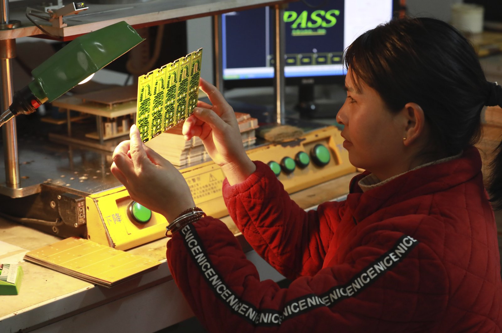 A worker examines a printed circuit board at a factory in Hangzhou in eastern Zhejiang province, China, Jan. 7, 2024. (AP Photo)