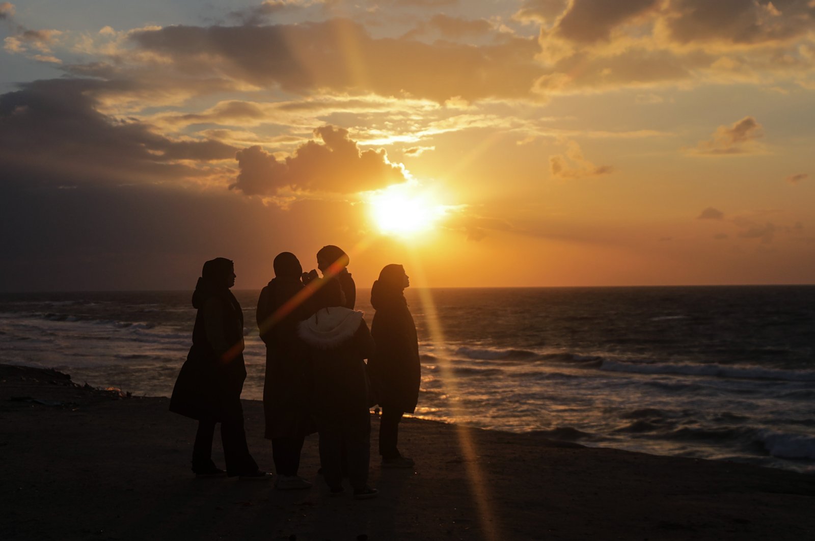 Palestinian girls look at the sunset on a beach in Deir Al-Balah town, southern Gaza Strip, Palestine, Jan. 30, 2024. (EPA Photo)