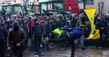 A person throws eggs toward the police officers as Belgian farmers use their tractors to block the European Union headquarters, protesting price pressure, taxes and green regulation, on the day of the EU summit in Brussels, Belgium, Feb. 1, 2024. (Reuters Photo)
