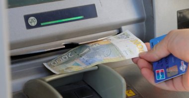 A man withdraws Serbian dinar currency from an ATM in Mitrovica, Kosovo, Feb. 1, 2024. (Reuters Photo)