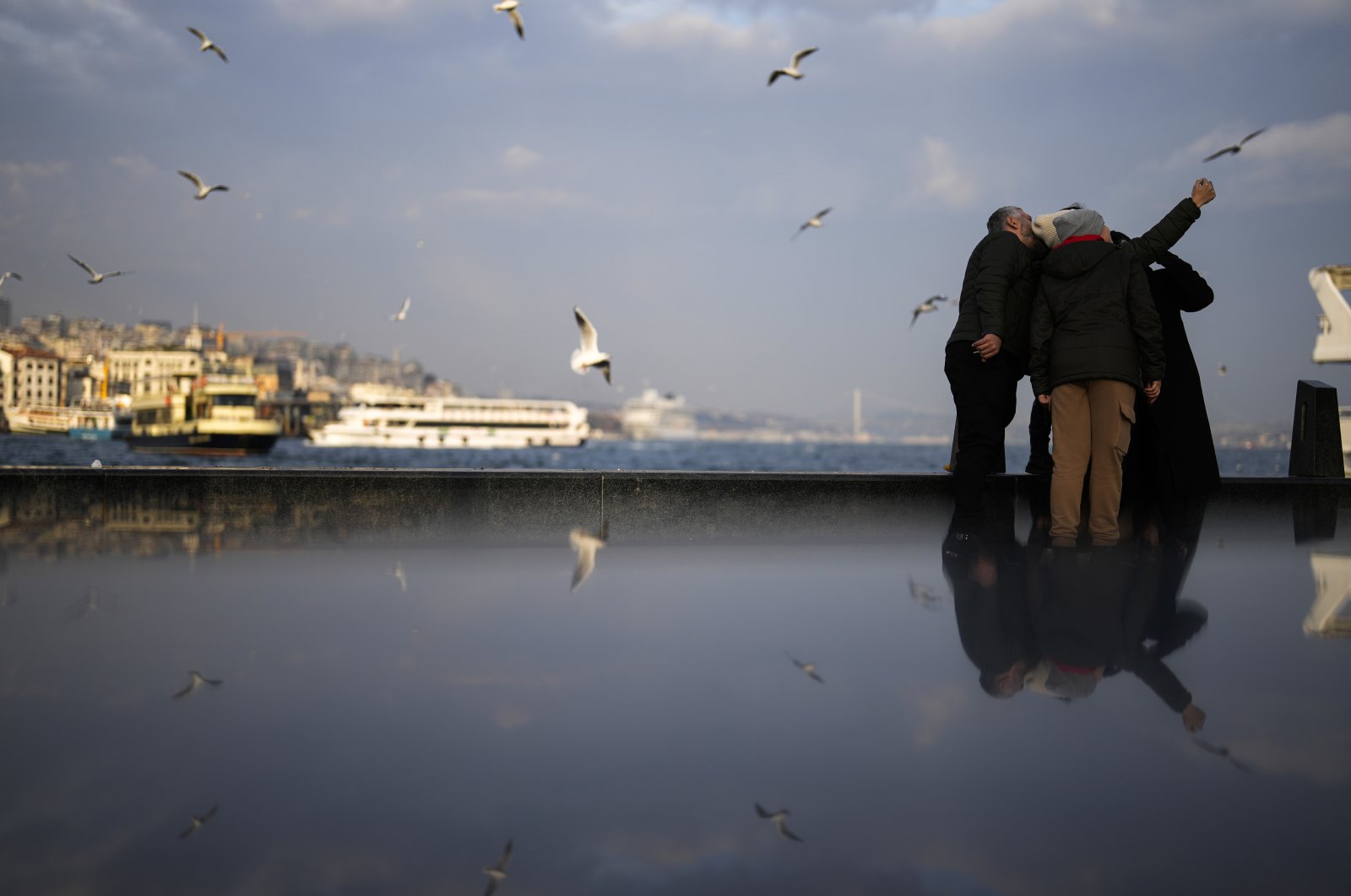 People pose for a photograph at Eminönü sea promenade in Istanbul, Türkiye, Jan. 25, 2024. (AP Photo)
