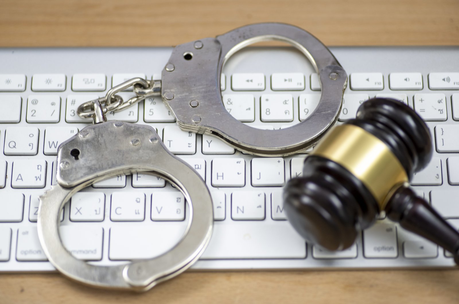 Handcuffs and a wooden gavel on a keyboard. (Getty Images Photo)