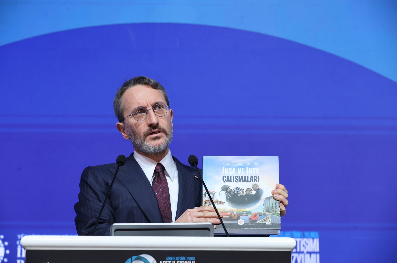 Fahrettin Altun shows a book about post-quake efforts during the symposium, in the capital Ankara, Türkiye, Feb. 5, 2024. (AA Photo)