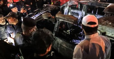 People, rescuers and security forces gather around a vehicle hit by a U.S. drone strike, in Baghdad, Iraq, Feb. 7, 2024. (AFP Photo)