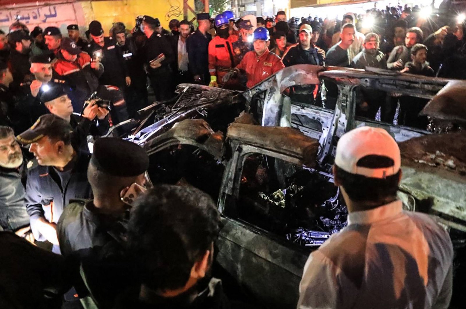 People, rescuers and security forces gather around a vehicle hit by a U.S. drone strike, in Baghdad, Iraq, Feb. 7, 2024. (AFP Photo)