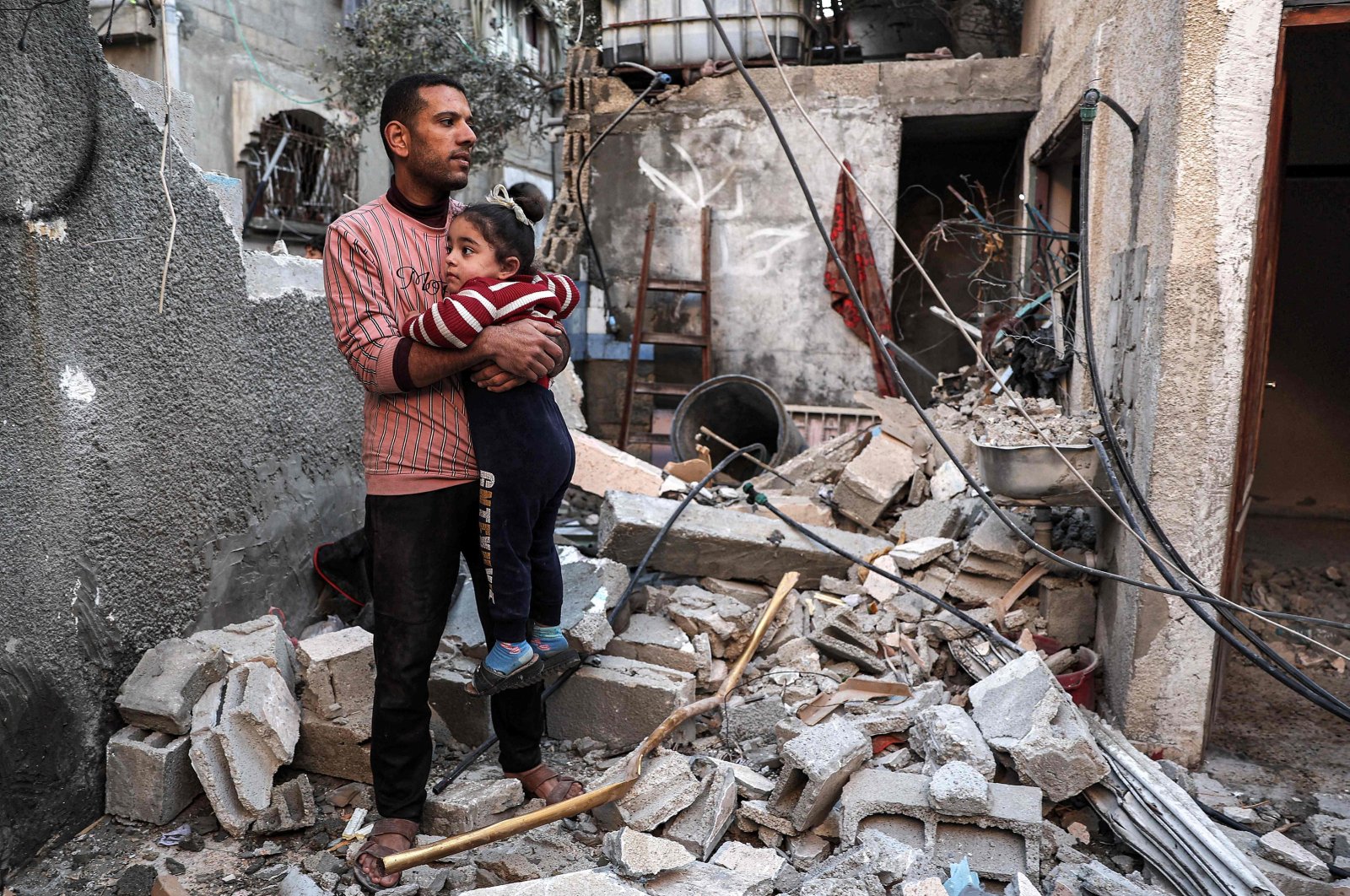 A Palestinian man holds a little girl as he stands amid debris inside an apartment destroyed by Israeli bombardment on Rafah, Gaza Strip, Palestine, Feb. 8, 2024. (AFP Photo)