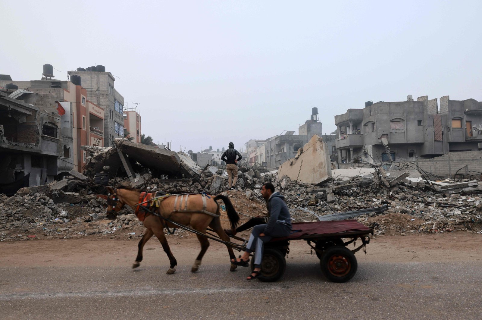A man rides a horse-pulled cart along a street ravaged by Israeli bombing, Rafah, southern Gaza, Feb. 9, 2024. (AFP Photo)