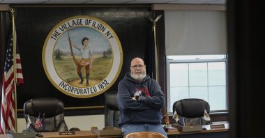 Ilion Mayor John Stephens poses for a picture in front of the seal of the village at the municipal building in Ilion, N.Y., U.S., Feb. 1, 2024. (AP Photo)