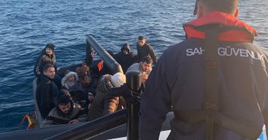 A Turkish officer looks on as a coast guard boat pulls up to a group of migrants floating off the coast of western Izmir province, Türkiye, Feb. 10, 2024. (AA Photo)