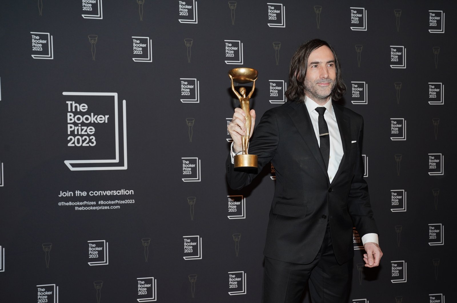 Paul Lynch holds up trophy after being named the winner of the 2023 Booker Prize for the novel "Prophet Song," at an award ceremony in Old Billingsgate, London, U.K., Nov. 26, 2023 (Getty Images Photo)