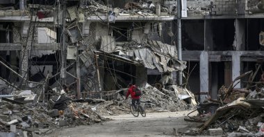 A Palestinian child rides a bike past destroyed houses amid Israeli attacks on Al Bureije refugee camp, southern Gaza Strip, Feb. 13, 2024. (EPA Photo)