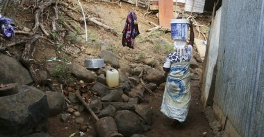 A woman carries a bucket of water on her head on the French Indian Ocean territory of Mayotte, Oct. 12, 2023. (AP Photos)