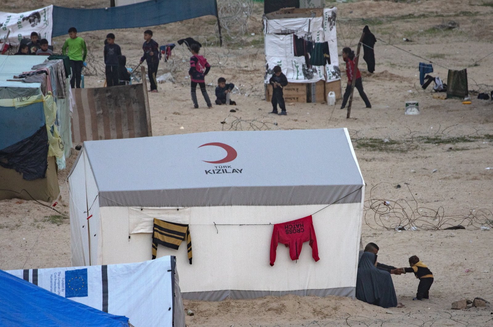 Displaced Palestinians sit while children play next to their tents at the beach, near the border separating the Gaza Strip and Egypt in the Rafah refugee camp, Gaza Strip, Palestine, Feb. 13, 2024. (EPA Photo)