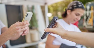 Two mobile users are using contactless mobile payment in Istanbul, Türkiye. (Getty Images Photo)