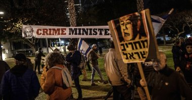 A protester hangs a banner during an anti-government demonstration in Tel Aviv, Isreal, Feb. 17, 2024. (AA Photo)