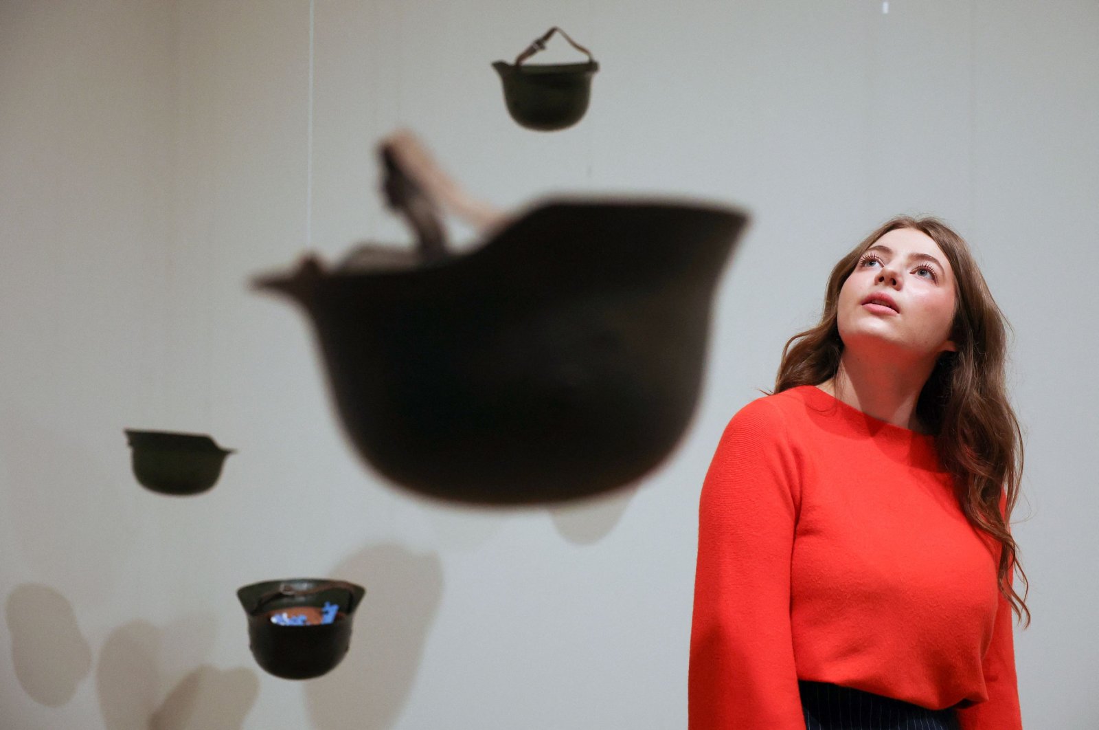 A gallery employee poses with an artwork entitled &quot;Helmets (Pieces of Sky)&quot; by Yoko Ono, Tate Modern, London, U.K., Feb. 13, 2024. (AFP Photo)