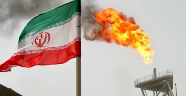 A gas flare on an oil production platform in the Soroush oil fields is seen alongside an Iranian flag in the Persian Gulf, Iran, July 25, 2005. (Reuters Photo)