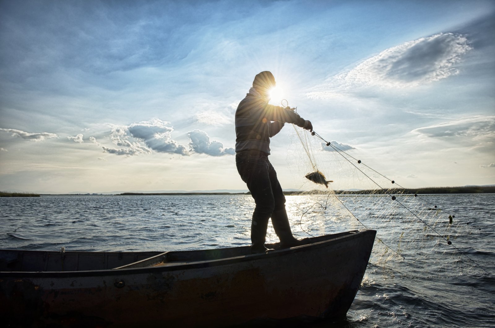 A fisherman reels in a catch on his boat, Çivril, Denizli, Türkiye, Feb. 19, 2024. (Getty Images)