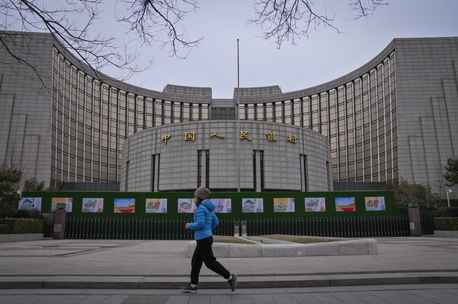 A woman jogs past the People&#039;s Bank of China, Beijing, China, Feb. 20, 2024. (AP Photo)