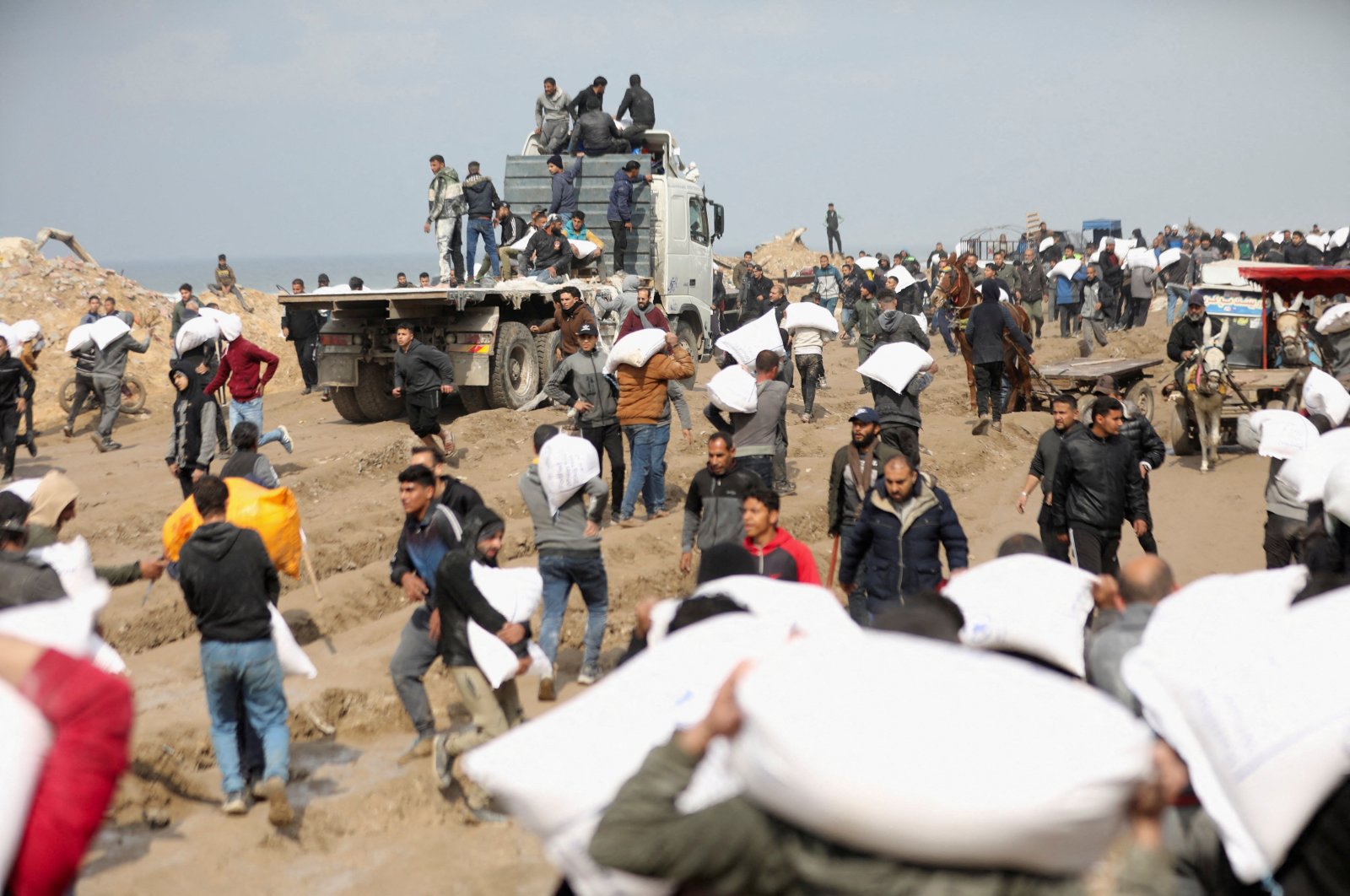 Palestinians carry bags of flour they grabbed from an aid truck in Gaza City, Palestine, Feb. 19, 2024. (Reuters Photo)