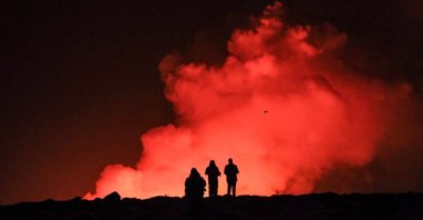 A group of people observe molten lava and billowing smoke from a volcanic eruption near Grindavik, western Iceland, Feb. 8, 2024. (AFP Photo)
