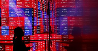 A visitor stands next to an electronic screen displaying Japan's Nikkei stock prices quotation board as the average surged past an all-time record high scaled in December 1989, inside a building in Tokyo, Japan, Feb. 22, 2024. (Reuters Photo)