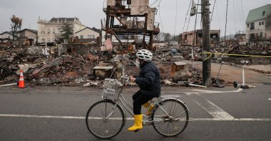 A person rides a bicycle past the rubble of buildings destroyed by a fire in the popular Asaichi Dori area in the city of Wajima, one month after a major 7.5 magnitude earthquake struck the Noto region, Ishikawa Prefecture, Japan, Feb. 1, 2024. (AFP Photo)