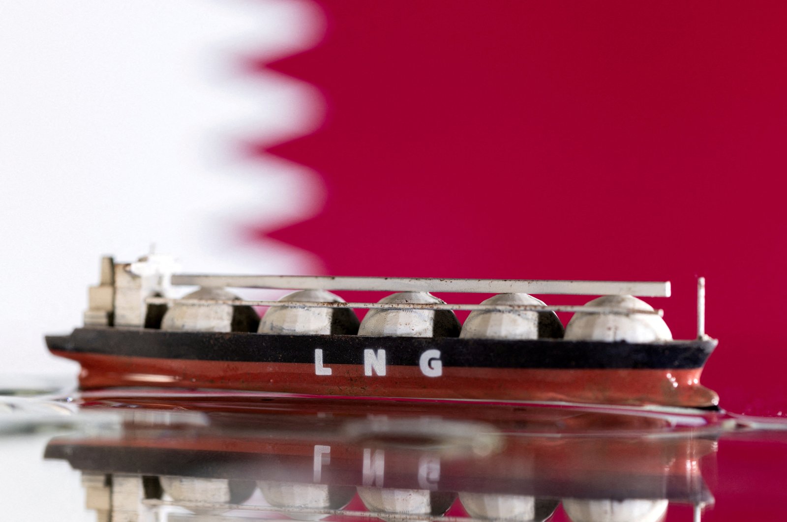 A model of an LNG tanker is seen in front of Qatar&#039;s flag in this illustration taken May 19, 2022. (Reuters Photo)