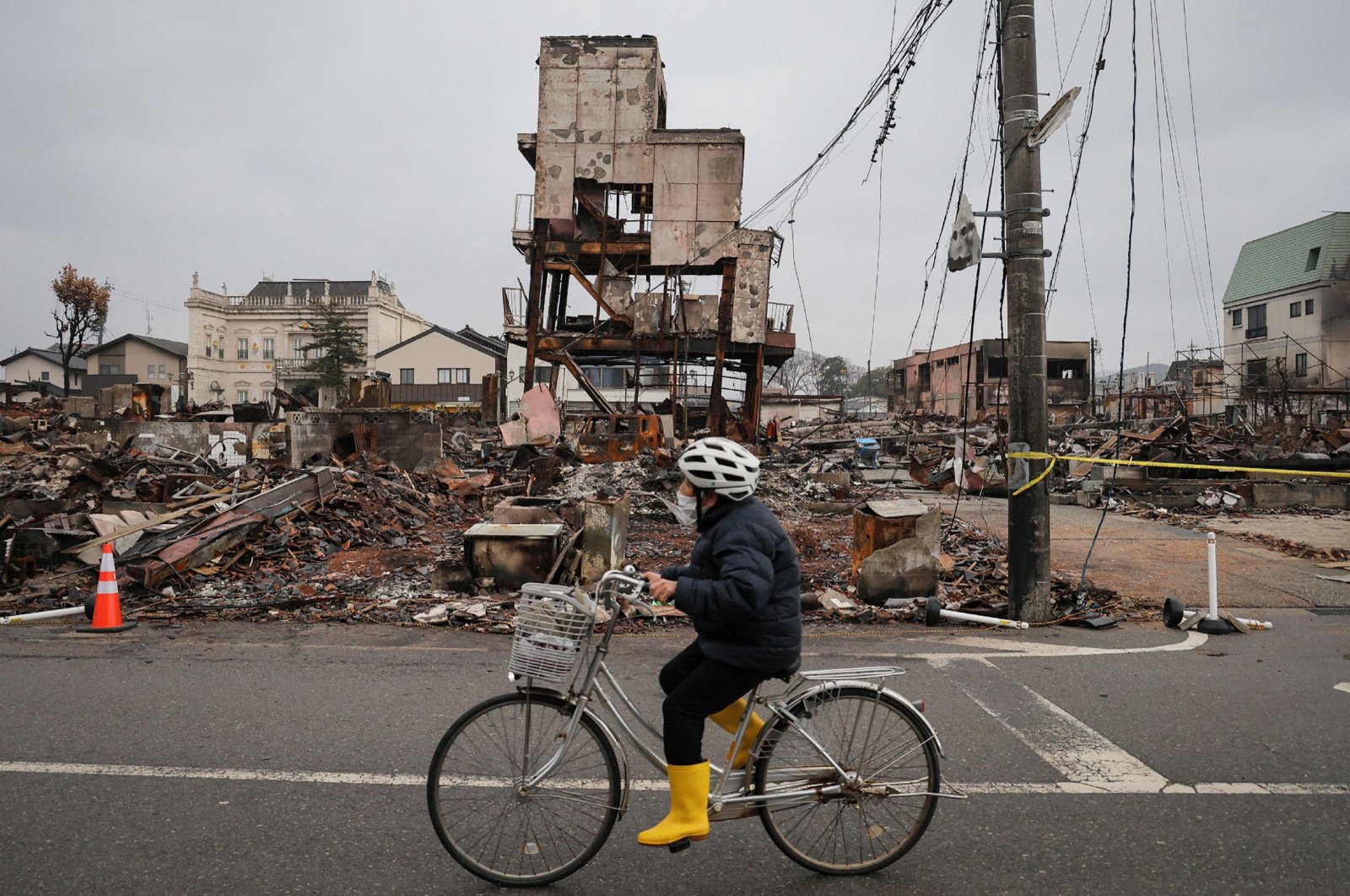 A person rides a bicycle past the rubble of buildings destroyed by a fire in the popular Asaichi Dori area in the city of Wajima, one month after a major 7.5 magnitude earthquake struck the Noto region, Ishikawa Prefecture, Japan, Feb. 1, 2024. (AFP Photo)