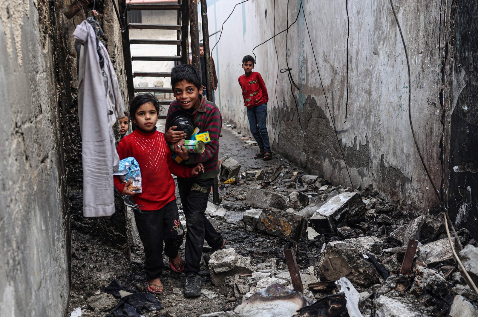 Children carry food items salvaged from their damaged home, following overnight Israeli bombardment in Rafah, southern Gaza Strip, Palestine, Feb. 25, 2024. (AFP Photo)