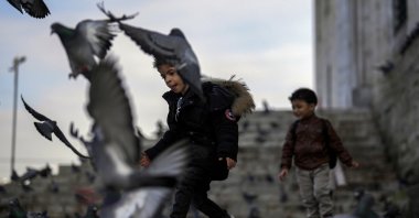 Children play with pigeons next to Yeni Cami (New Mosque) in Istanbul, Türkiye, Jan. 17, 2024. (AP Photo)