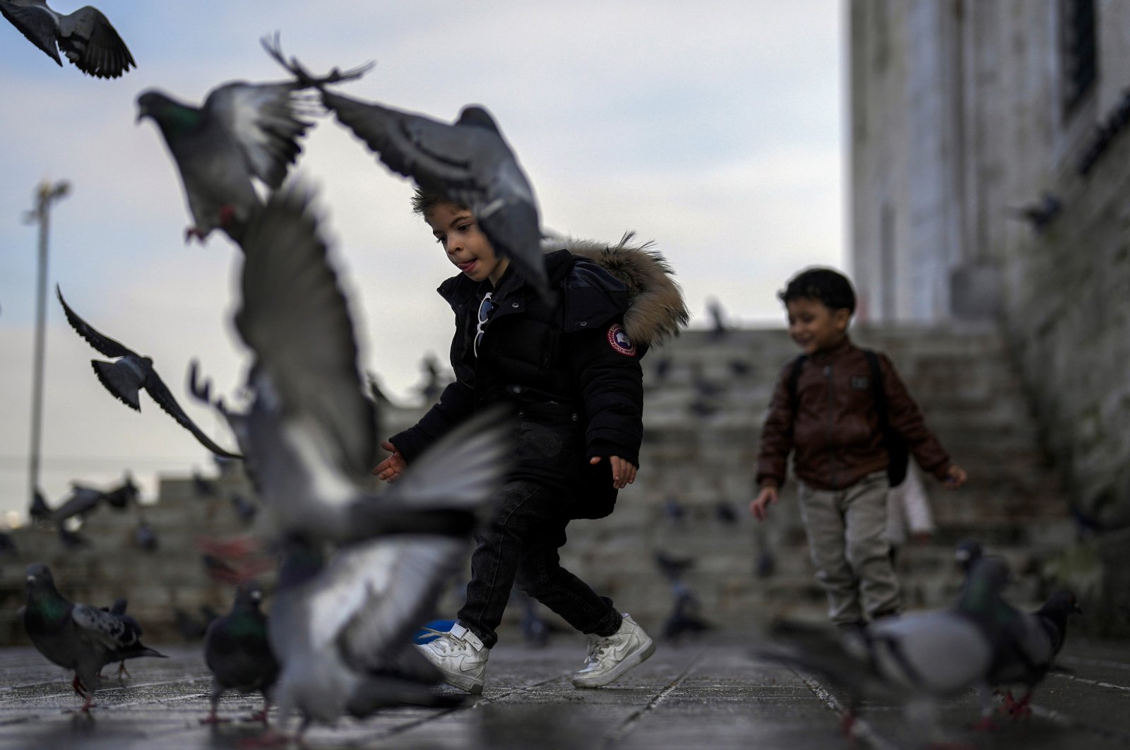 Children play with pigeons next to Yeni Cami (New Mosque) in Istanbul, Türkiye, Jan. 17, 2024. (AP Photo)