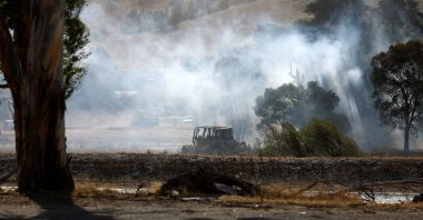 A Caterpillar vehicle sits on a field as a fire burns outside of Beaufort, Victoria, Australia, Feb. 28, 2024. (EPA Photo) 