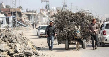 Palestinian men lead a donkey-pulled cart past the ruins of buildings in the Maghazi refugee camp, in central Gaza, Palestine, Feb. 27, 2024. (AFP Photo)