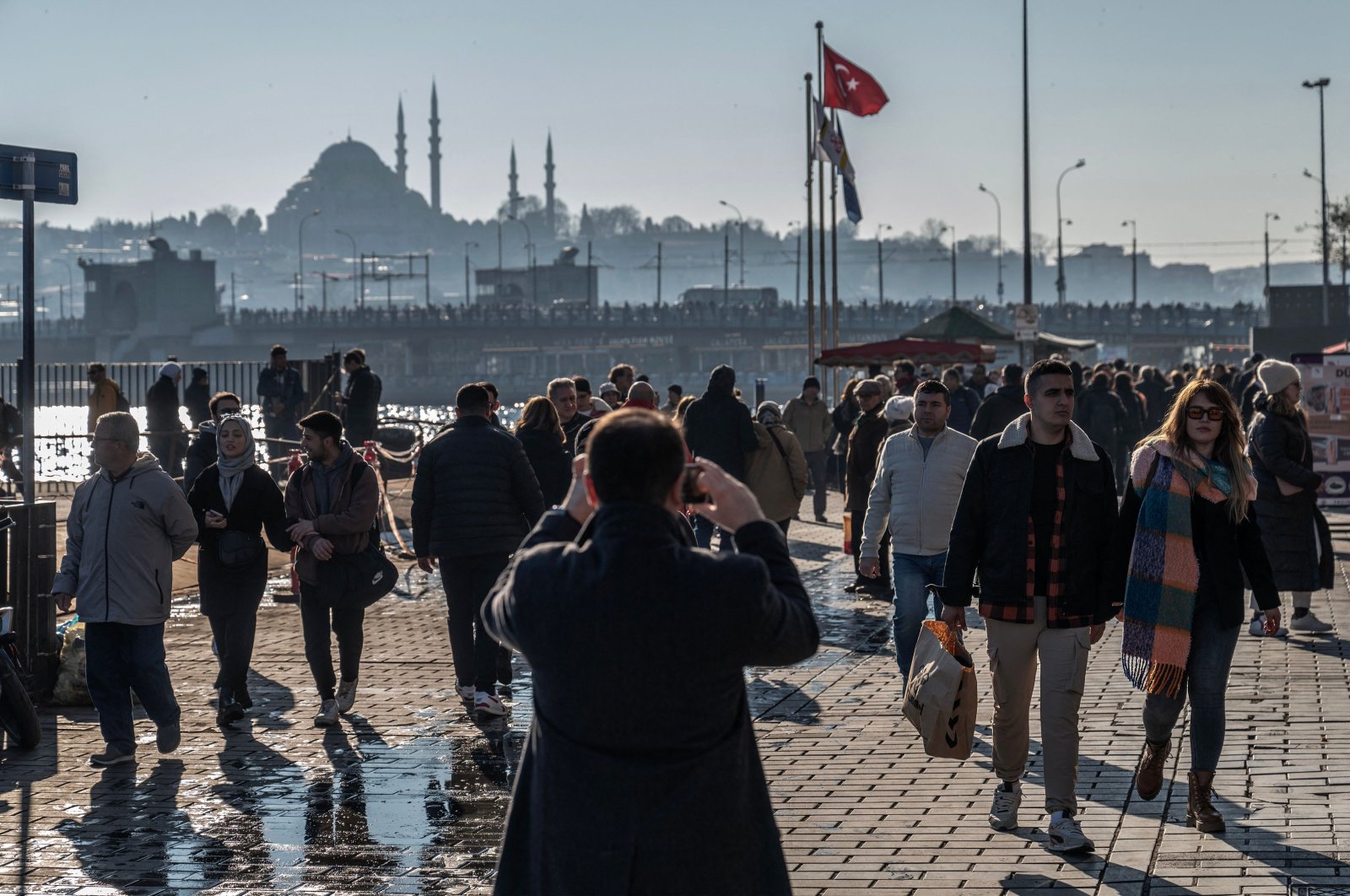 Pedestrians walk next to a ferryboat port in the Karaköy district, with Süleymaniye Mosque and Galata Bridge seen in the background, Istanbul, Türkiye, Feb. 22, 2024. (AFP Photo)