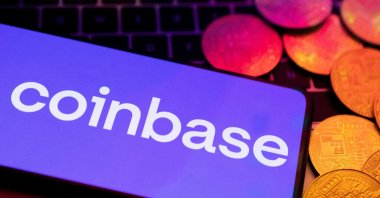 A smartphone with a displayed Coinbase logo and representation of cryptocurrencies are placed on a keyboard in this illustration taken on June 8, 2023. (Reuters Photo)