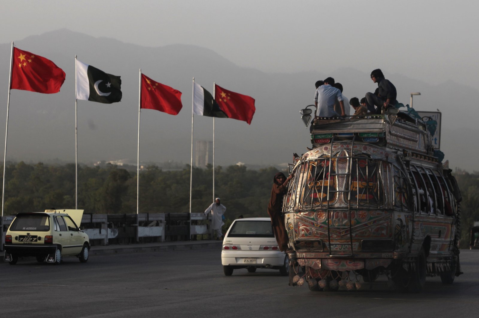 People sit on top of a bus as it passes flags of Pakistan and China displayed along a road, ahead of Chinese Premier Li Keqiang&#039;s visit to Islamabad, Pakistan, May 21, 2013. (Reuters Photo)