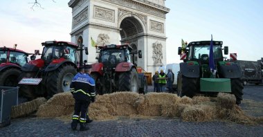 Police officers look at tractors parked next to the Arc de Triomphe on Champs-Elysees during a protest by the French farmers&#039; union, Paris, France, March 1, 2024. (AFP Photo)