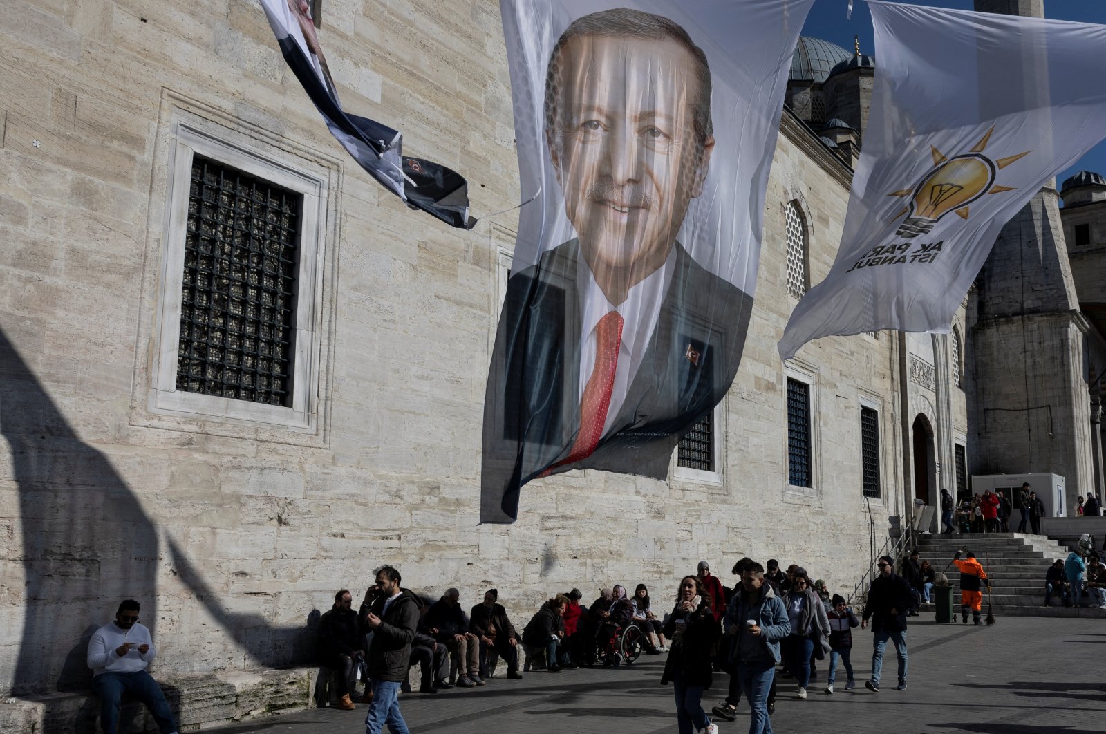 People walk under election posters for President Recep Tayyip Erdoğan and his ruling Justice and Development Party (AK Party) flags in Istanbul, Türkiye, Feb. 20, 2024. (Reuters Photo)
