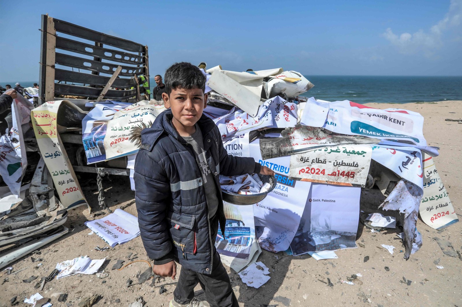 A boy walks past a truck carrying humanitarian aid that was hit by an Israeli airstrike on the main coastal road in Deir el-Balah, central Gaza Strip, Palestine, March 3, 2024. (AFP Photo)
