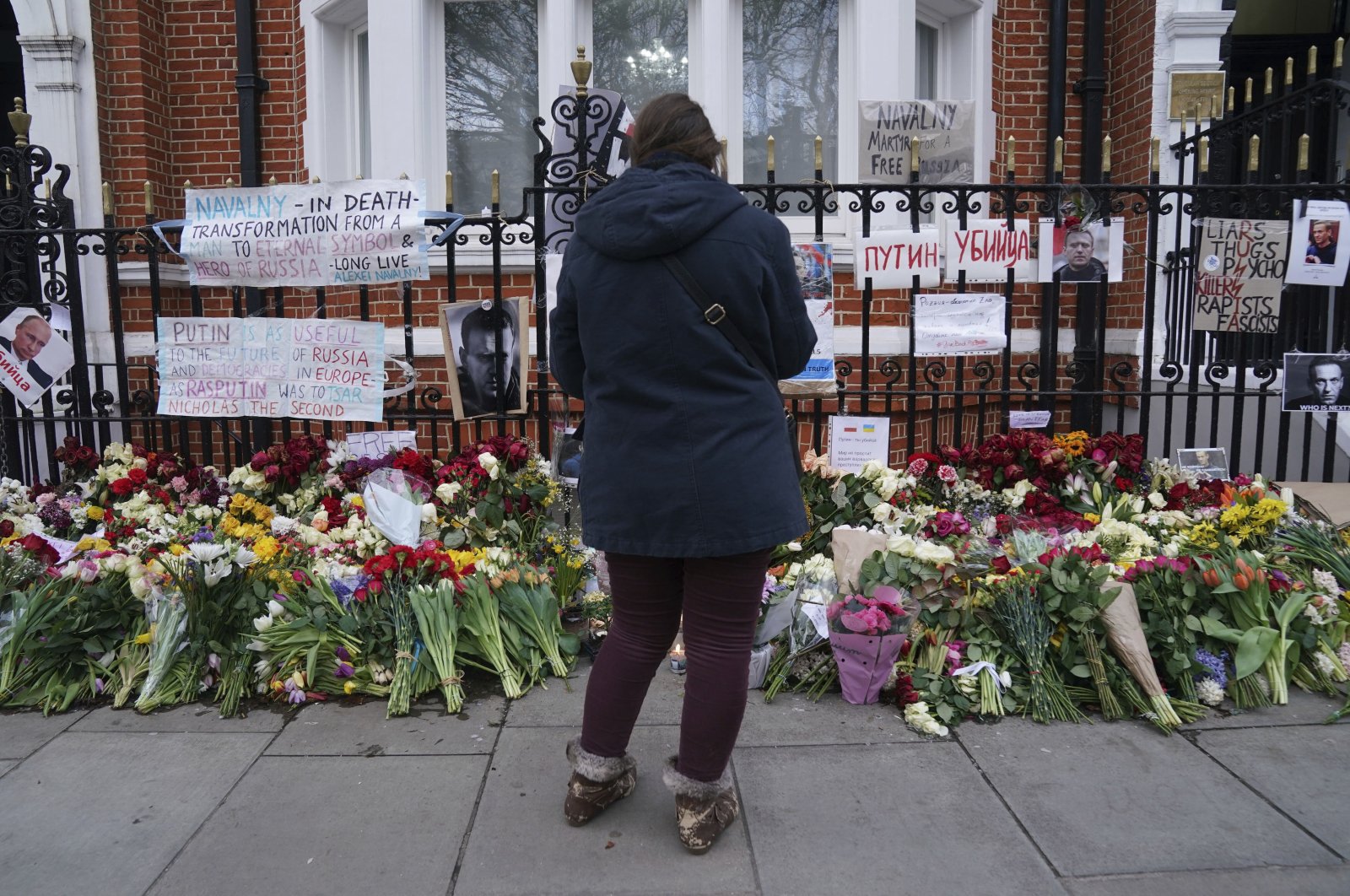 A person looks at flowers outside the Russian Embassy in London, on the day of the funeral of Russian opposition leader Alexei Navalny which took place in Moscow, Russia, Friday March 1, 2024. (AP Photo)