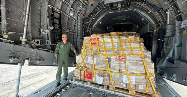 A Defense Ministry official poses next to crates of medical supplies on the ramp of a military transport plane headed for Gaza, Amman, Jordan, March 5, 2024. (AA Photo)