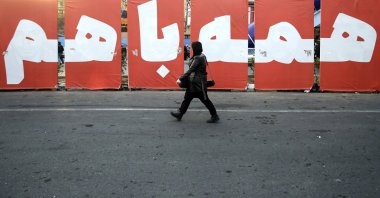 An Iranian woman walks past a huge banner reading in Persian 'All together for homeland' in a street in Tehran, Iran, March 4, 2024. (EPA Photo)