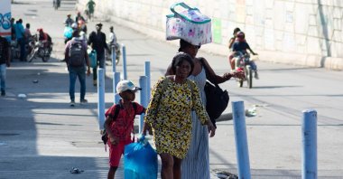 People living near the National Penitentiary, carry their belongings as they leave the area in Port-au-Prince, Haiti, March 4, 2024. (AFP Photo)